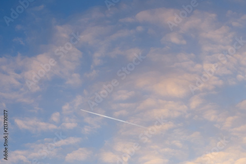 Airplane in blue cloudy sky on sunset. Place for the inscription, place for the text, copy place.