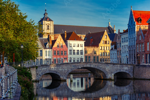 Scenic city view of Bruges canal with beautiful medieval colored houses  bridge and reflections in the evening gold hour  Belgium