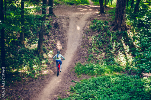 A cyclist in a helmet descends from the mountain on an orange bicycle