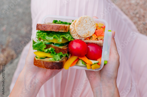 Young girl holding lunch box filled with sandwich photo