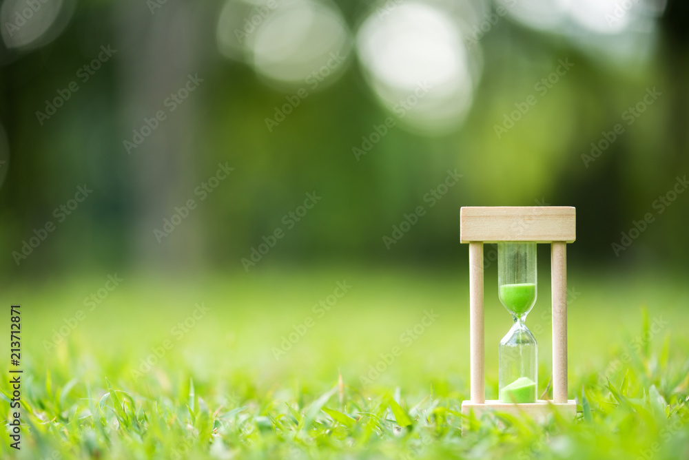 hourglass on green grass field , spring time
