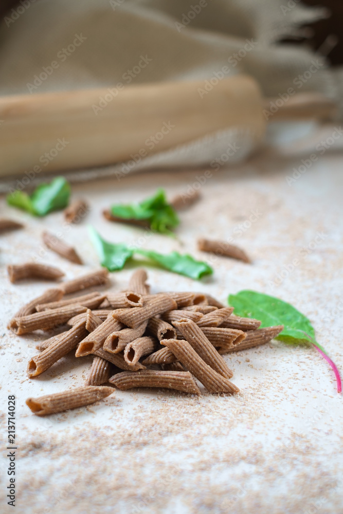 raw whole-grain pasta homemade on the table with flour