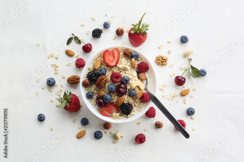 Oatmeal porridge in bowl topped with fresh blueberries, cranberries and homemade crunchy granola photo