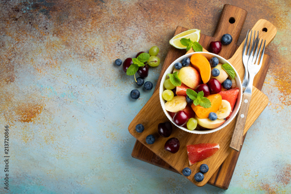 Bowl of healthy fresh fruit salad on a blue rusty background. Top view with copy space. Flat lay Bowl of healthy fresh fruit salad on a blue rusty background. Top view with copy space. Flat lay
