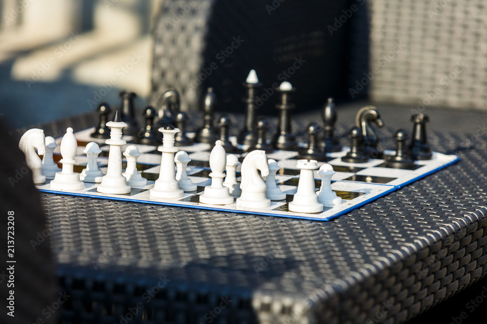 chessboard on the rattan table in the garden in the summer. Travel, vacation, holidays concept  Education concept, chess lesson, training, intellectual game