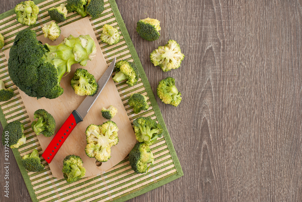 Sliced broccoli on a bamboo napkin. View from above. Inflorescences of cabbage broccoli on a wooden background. Preparation of dishes from vegetables. Sliced broccoli on a bamboo napkin. View from above. Inflorescences of cabbage broccoli on a wooden background. Preparation of dishes from vegetables.