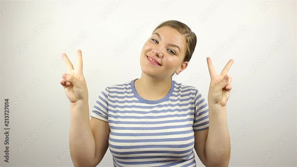 Beautiful young woman showing victory sign and smiling. Beautiful young woman showing victory sign and smiling.