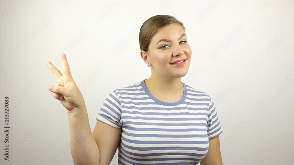 Beautiful young woman showing victory sign and smiling. Beautiful young woman showing victory sign and smiling.