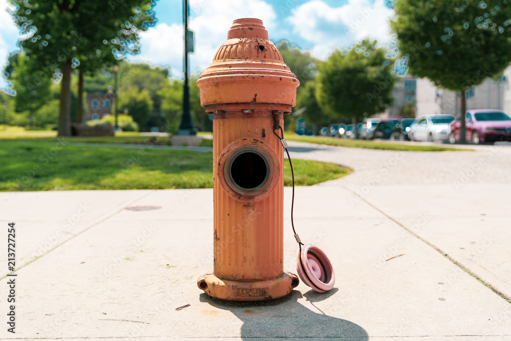 Orange Fire Hydrant Missing Cap at Philadelphia Park with Beautiful Blue Sky and Clouds Orange Fire Hydrant Missing Cap at Philadelphia Park with Beautiful Blue Sky and Clouds