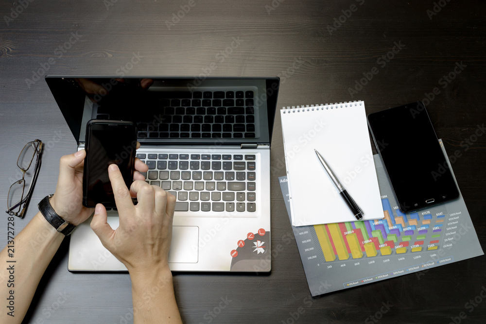 A man prints on a laptop, lying next to the phone, tablet glasse A man prints on a laptop, lying next to the phone, tablet glasse