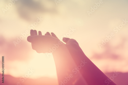 Woman hands place together like praying in front of nature green background.