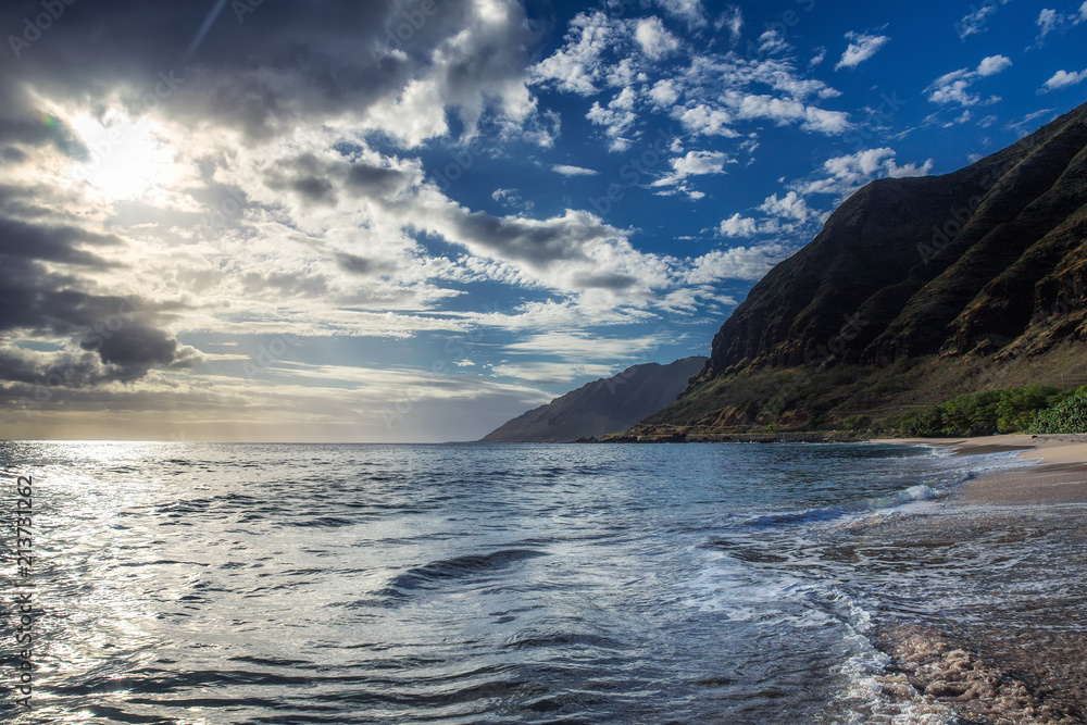 Sun shining through the clouds at sandy beach with waves Sun shining through the clouds at sandy beach with waves