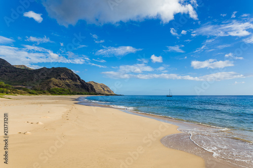 Makua beach view with beatiful mountains and a sailboat in the background  Oahu island  Hawaii