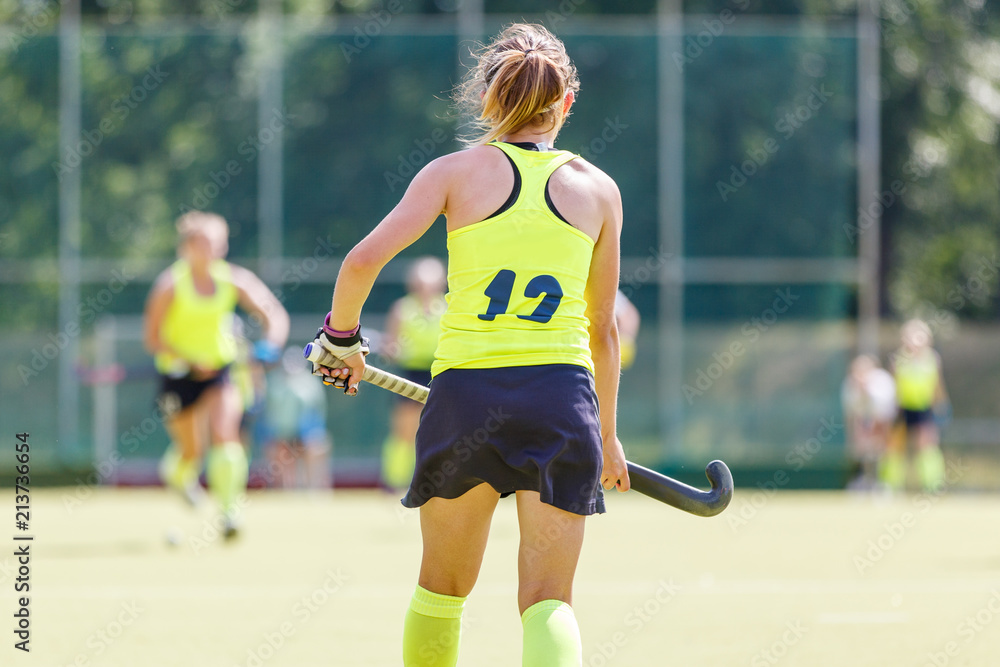 Fototapeta premium Young field hockey player girl with stick in the game. Back view