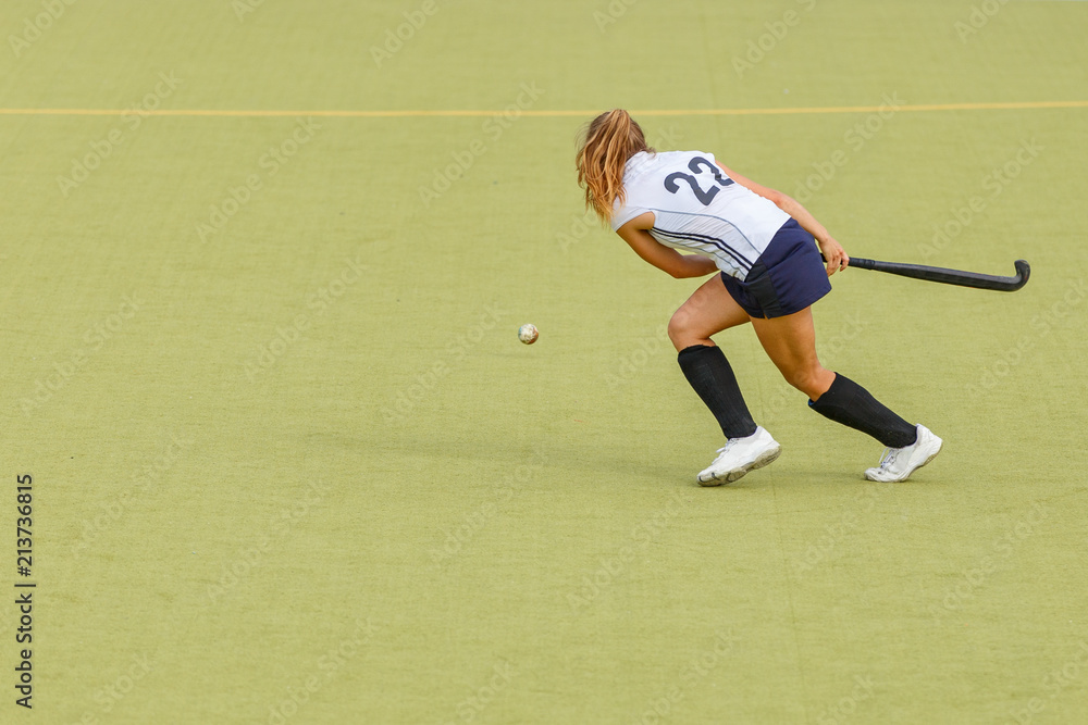 Young hockey player woman with ball in attack playing field hockey game