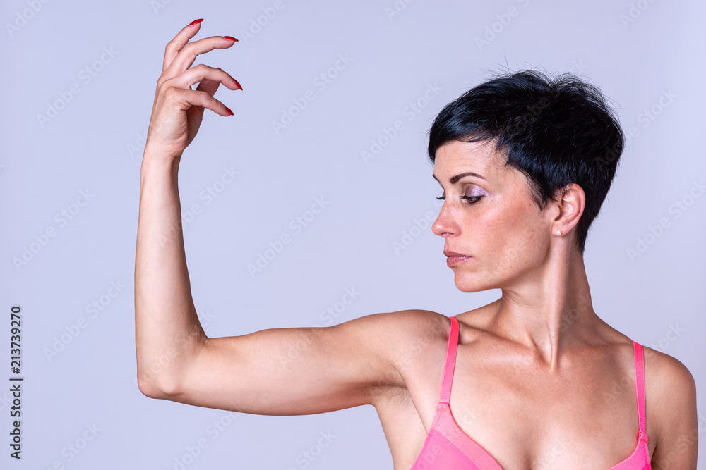 Serious woman in pink bra holding up arm Stock Photo