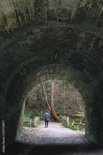 Lone man exiting at end of concrete tunnel with garden and tree at background © Jeffery