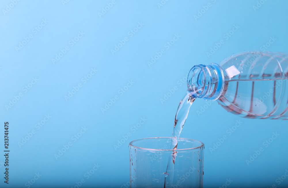 Closeup of pouring mineral water from bottle into glass.