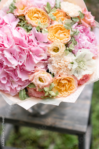 Beautiful pink summer bouquet on wooden table. Arrangement with mix flowers. The concept of a flower shop. Content for the catalog photo