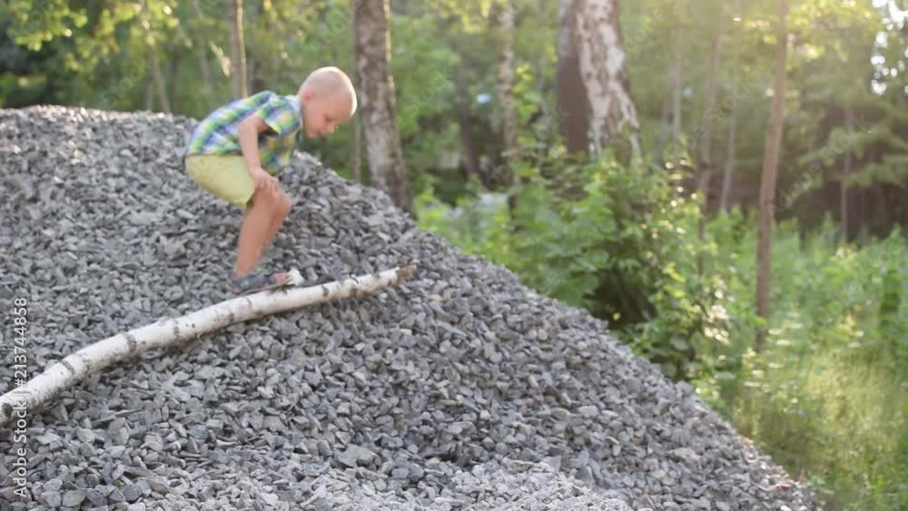 A little boy is climbing a pile of rubble. A little boy is climbing a pile of rubble.