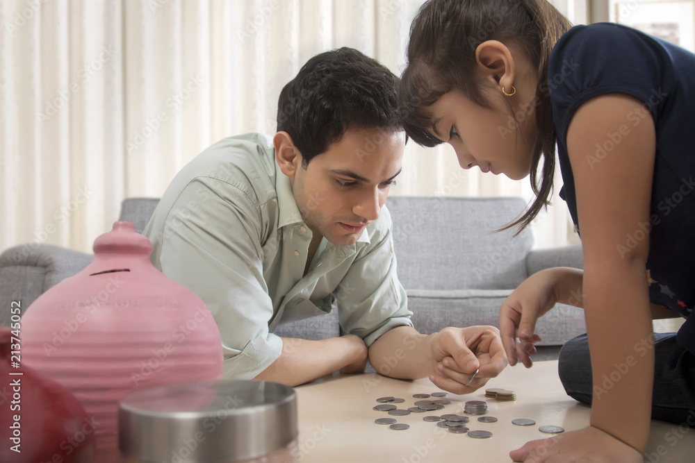 Father and daughter counting piggy bank coins Father and daughter counting piggy bank coins