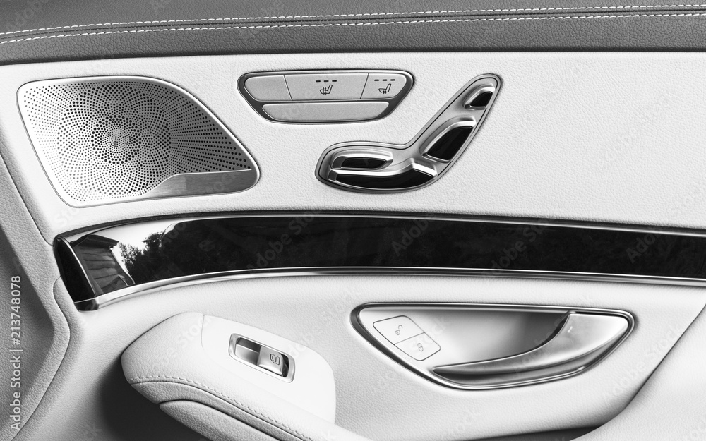 Door handle with Power seat control buttons of a luxury passenger car. White leather interior of the luxury modern car. Modern car interior details. Car detailing. Black and white