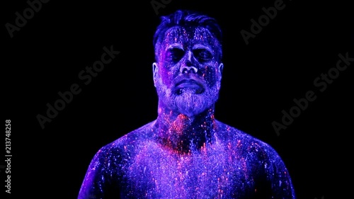 Concept. Portrait of a bearded man. The man is painted in ultraviolet powder photo