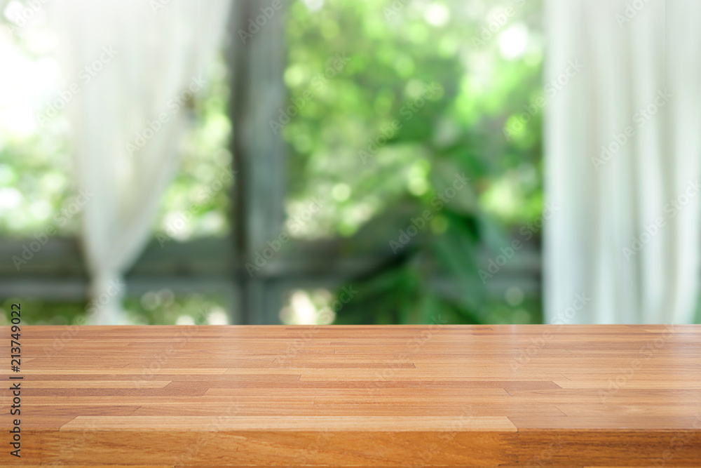 Empty of wood table top on blur of abstract green from garden with sunlight and curtain window Empty of wood table top on blur of abstract green from garden with sunlight and curtain window