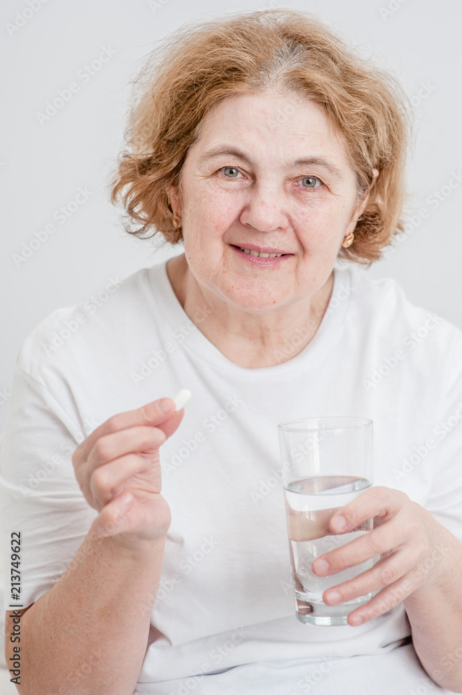 Happy senior woman holding pills and glass of water Happy senior woman holding pills and glass of water