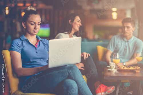 Young female student is using laptop computer in cafe