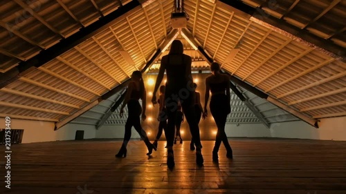 silhouettes of dancing girls. go-go dance. Closeup dance performance of pretty female group on a dark stage with yellow lights. team dance of women in high heels. slow motion photo