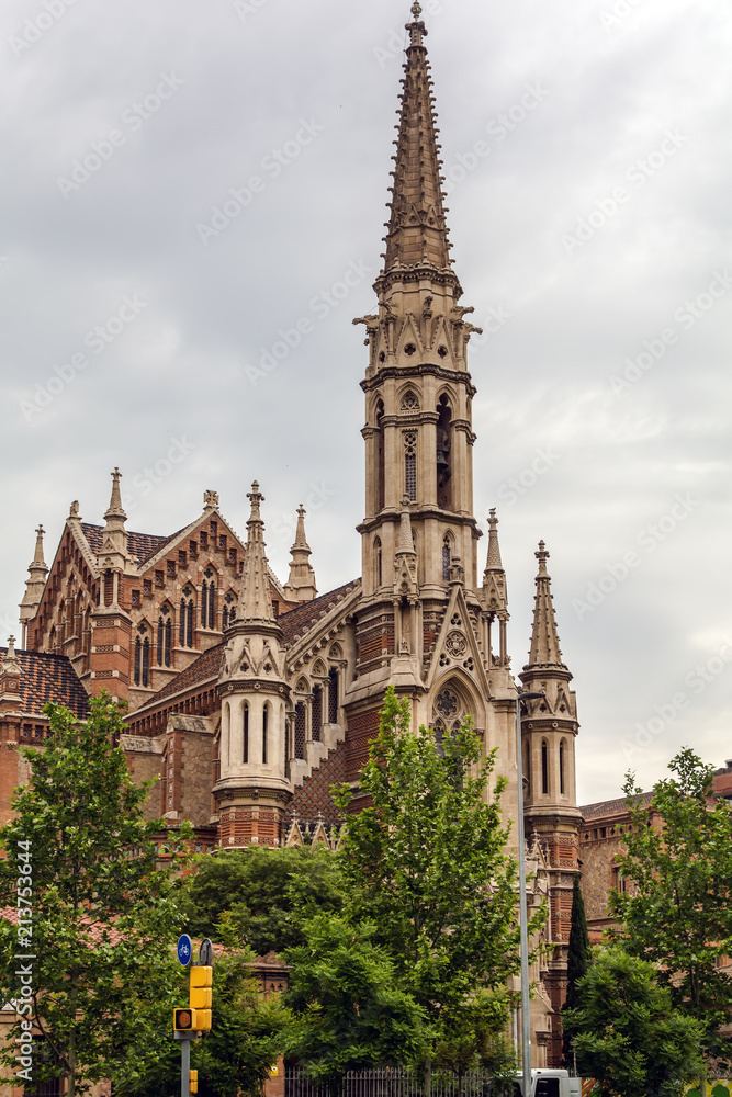 Neogothic parish church of Sant Francesc de Sales in Barcelona. The long and slender bell tower is flanked by two lateral pinnacles that reproduce in smaller scale the central tower.