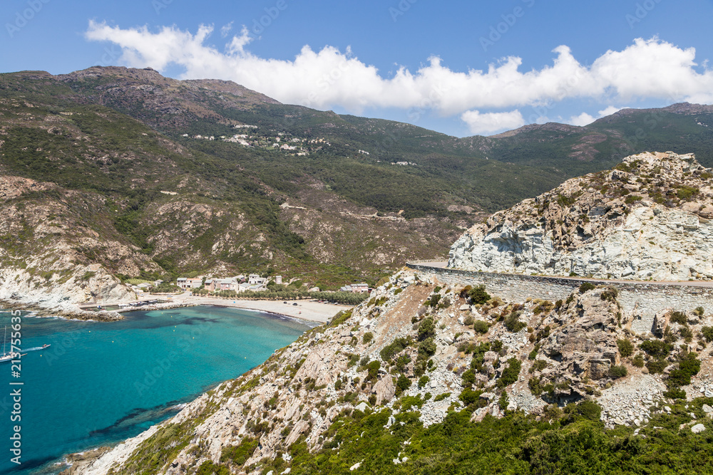 Stunning coastal road by a beautiful bay with turquoise water in Corsica in France near the Ile Rousse village.