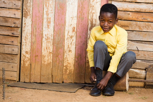 Black boy sitting down and tieing his shoes