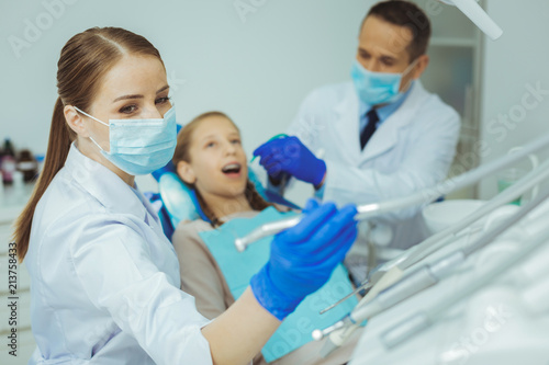 Look at this. Worried teenager keeping mouth opened while visiting dentist cabinet