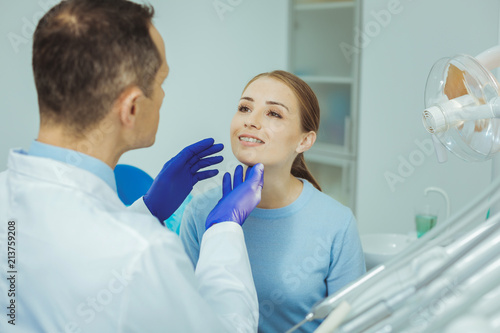 Visit doctor. Serious dentist examining his patient, working in clinic