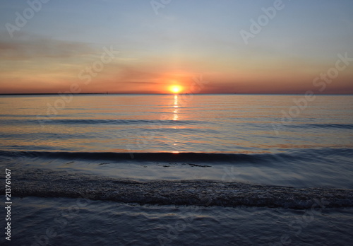 The Sun casts orange shades across an evening sky at Mindil Beach (Darwin, Northern Territory, Australia). photo