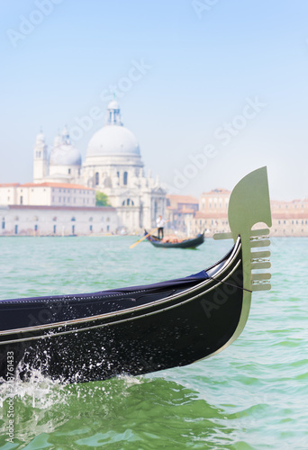 Traditional venetian gondola and gondolier with tourists between Grand Canal and Giudecca Canal of Venice city against basilica Santa Maria della Salute background. Italy. © EMrpize