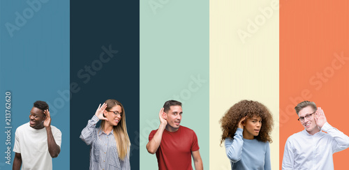 Group of people over vintage colors background smiling with hand over ear listening an hearing to rumor or gossip. Deafness concept.