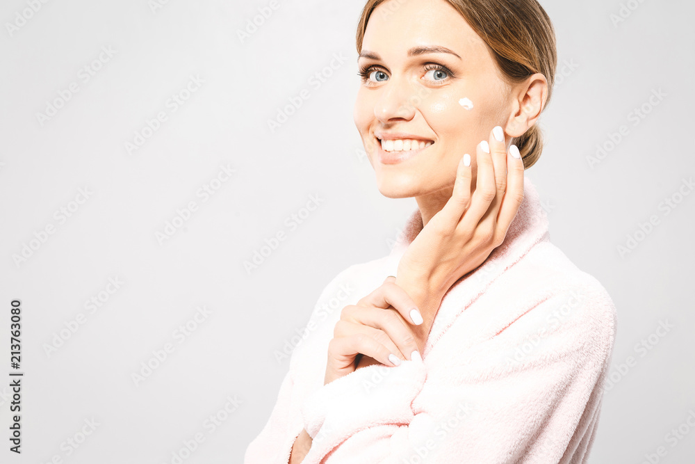 Portrait of young beautiful woman smiling while taking some facial cream isolated on white background with copy space. Portrait of young beautiful woman smiling while taking some facial cream isolated on white background with copy space.