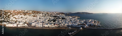 Fototapeta Naklejka Na Ścianę i Meble -  Aerial ultra wide panoramic drone view of iconic chora of Mykonos island featuring picturesque little Venice and church of Paraportiani at sunset, Cyclades, Aegean, Greece