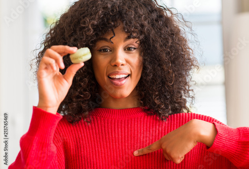 African american woman holding macaron with surprise face pointing finger to himself © Krakenimages.com