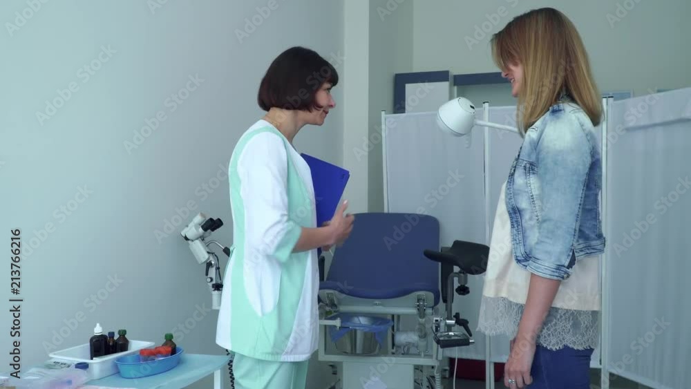 Gynecologist greeting young woman and invite her to gynecological chair Gynecologist greeting young woman and invite her to gynecological chair