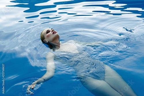 gorgeous young woman in clear blue water of smimming pool