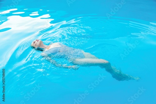 gorgeous young woman in clear blue water of smimming pool