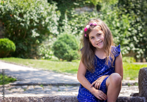 Portrait of a smiling beautiful little girl in blue dress, in the park © hiddencatch