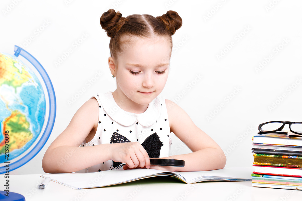 little girl at the table of a first-grader. Photo taken in the studio. little girl at the table of a first-grader. Photo taken in the studio.