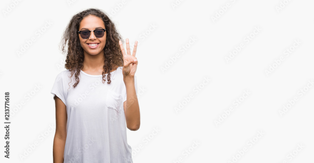 Young hispanic woman wearing sunglasses showing and pointing up with fingers number three while smiling confident and happy. Young hispanic woman wearing sunglasses showing and pointing up with fingers number three while smiling confident and happy.