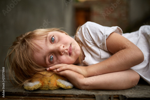 Portrait of unfortunate stray kid lying on the board in the dirty alley, shallow depth of field. photo
