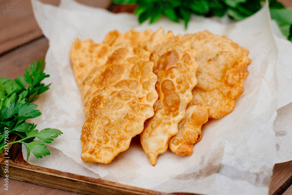 The Caucasian food is a patty made from thin unleavened dough with stuffed lamb and spicy seasonings. Cheburek - fried pie with meat and onions. Traditional dish of many tatar and eastern peoples. The Caucasian food is a patty made from thin unleavened dough with stuffed lamb and spicy seasonings. Cheburek - fried pie with meat and onions. Traditional dish of many tatar and eastern peoples.